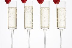 Plastic reusable champagne flutes with champagne and strawberries